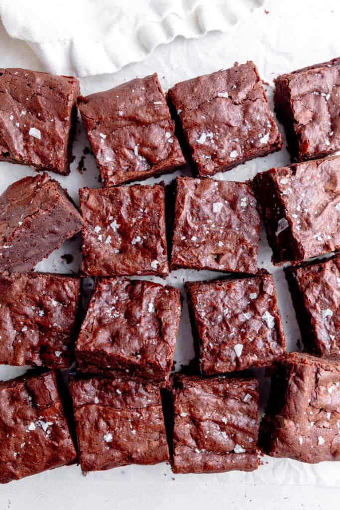 Vegan brownie squares on a white surface with a white linen napkin.