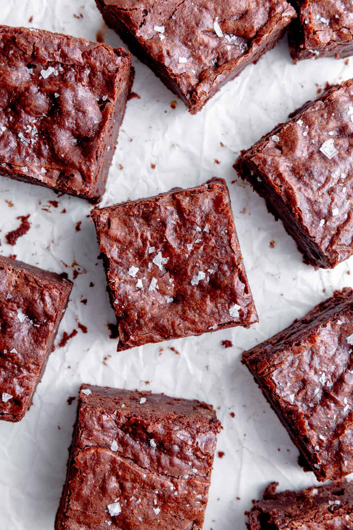 Brownies on a white surface, topped with flaky salt.