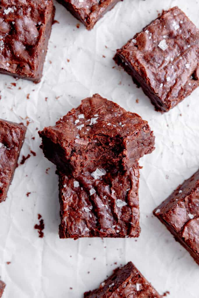 Vegan brownie with a bite taken out of it propped against another brownie.