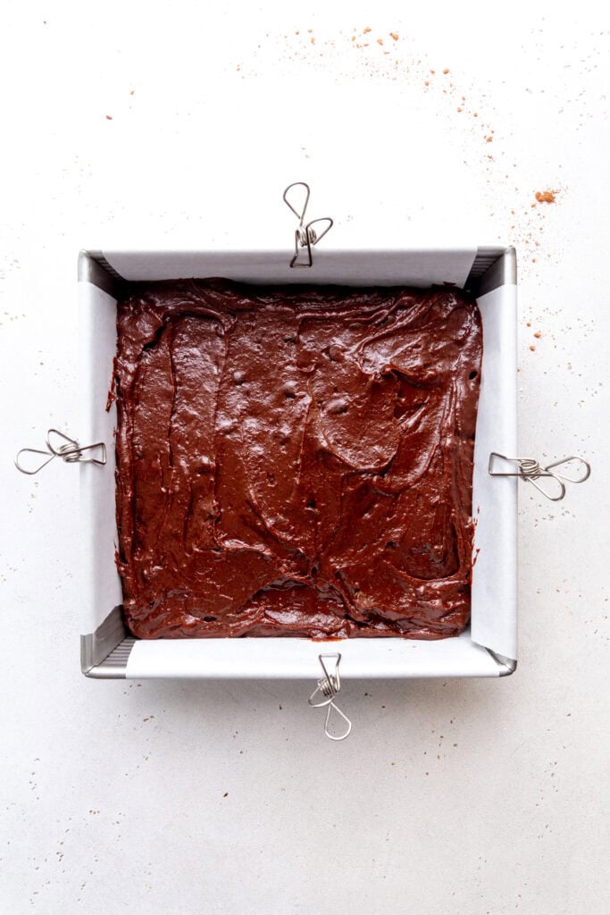 Unbaked brownies in a square pan.