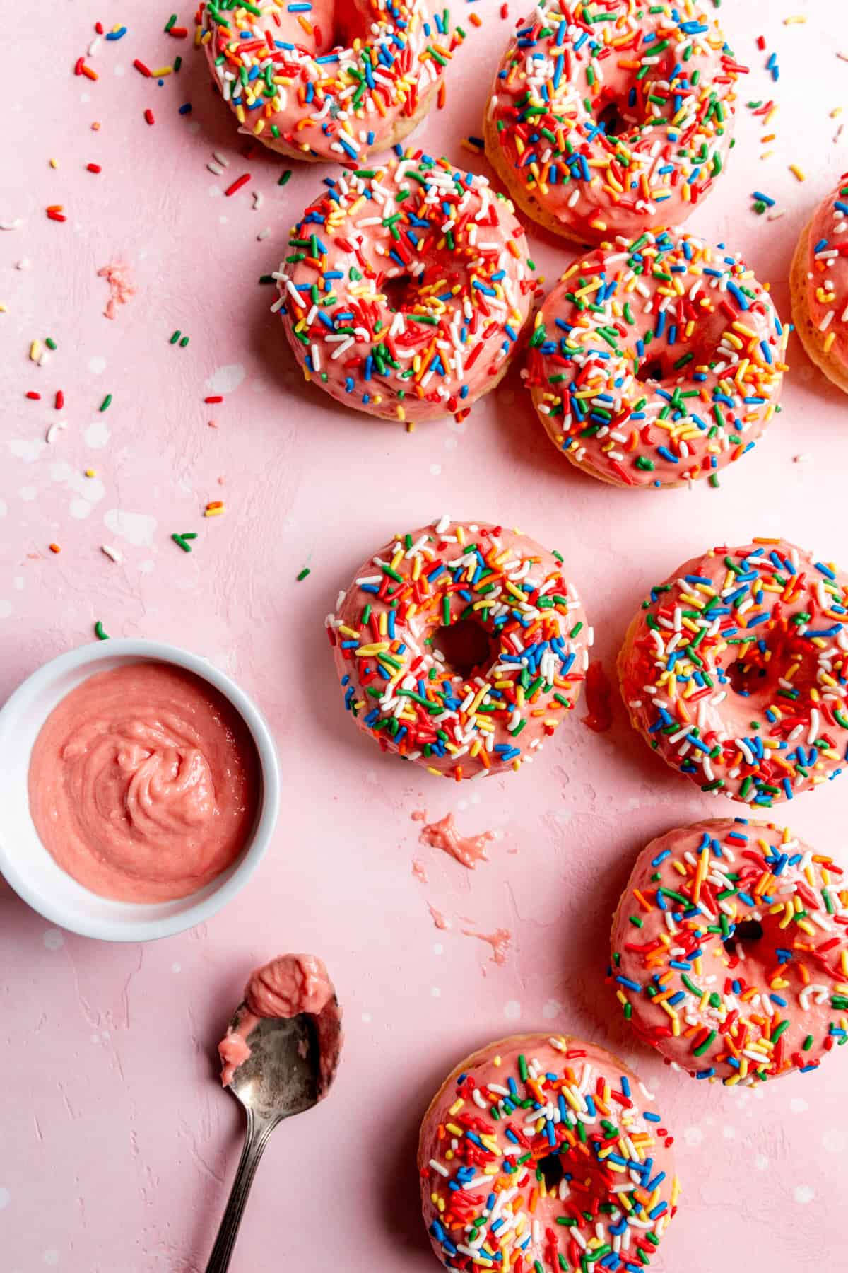 Pink sprinkle donuts and a bowl of strawberry icing.