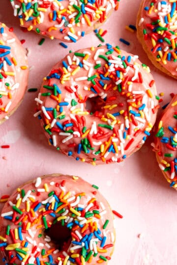 Baked donuts with strawberry icing and rainbow sprinkles.