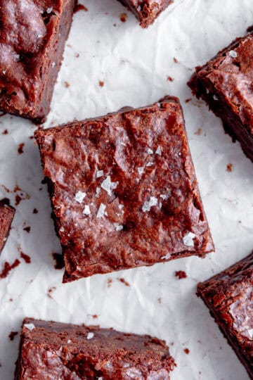 Brownies topped with flaky salt on a white background.