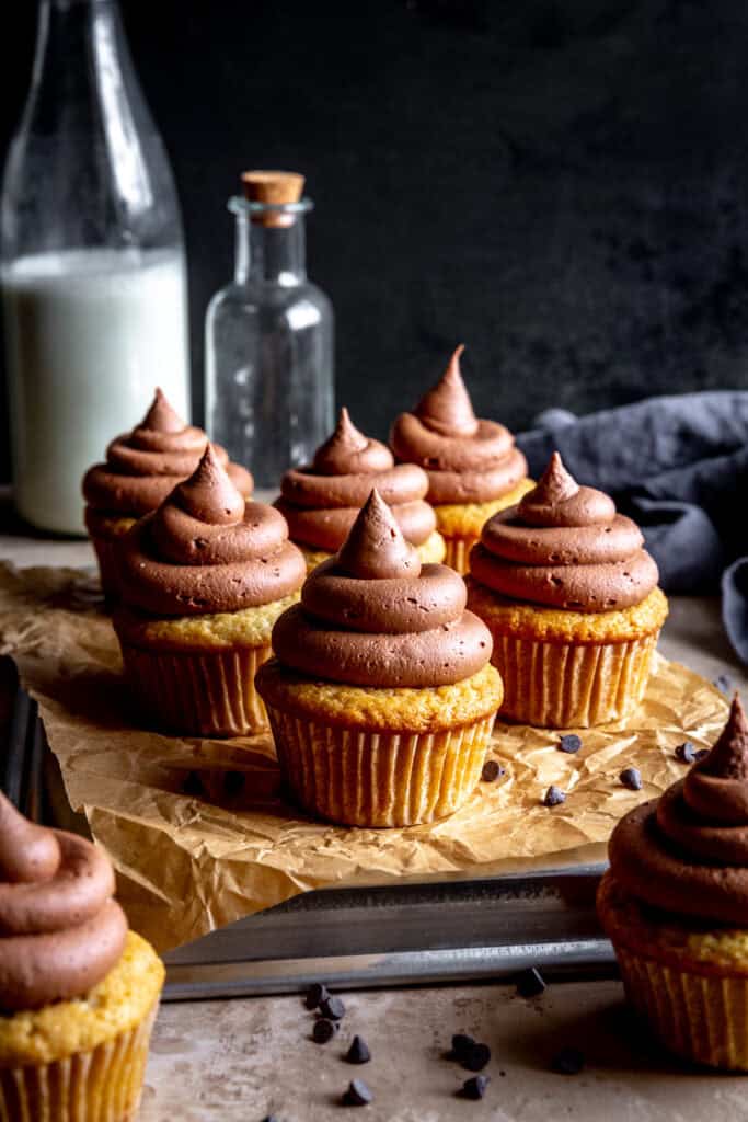 Cupcakes with chocolate frosting and a jug of milk.