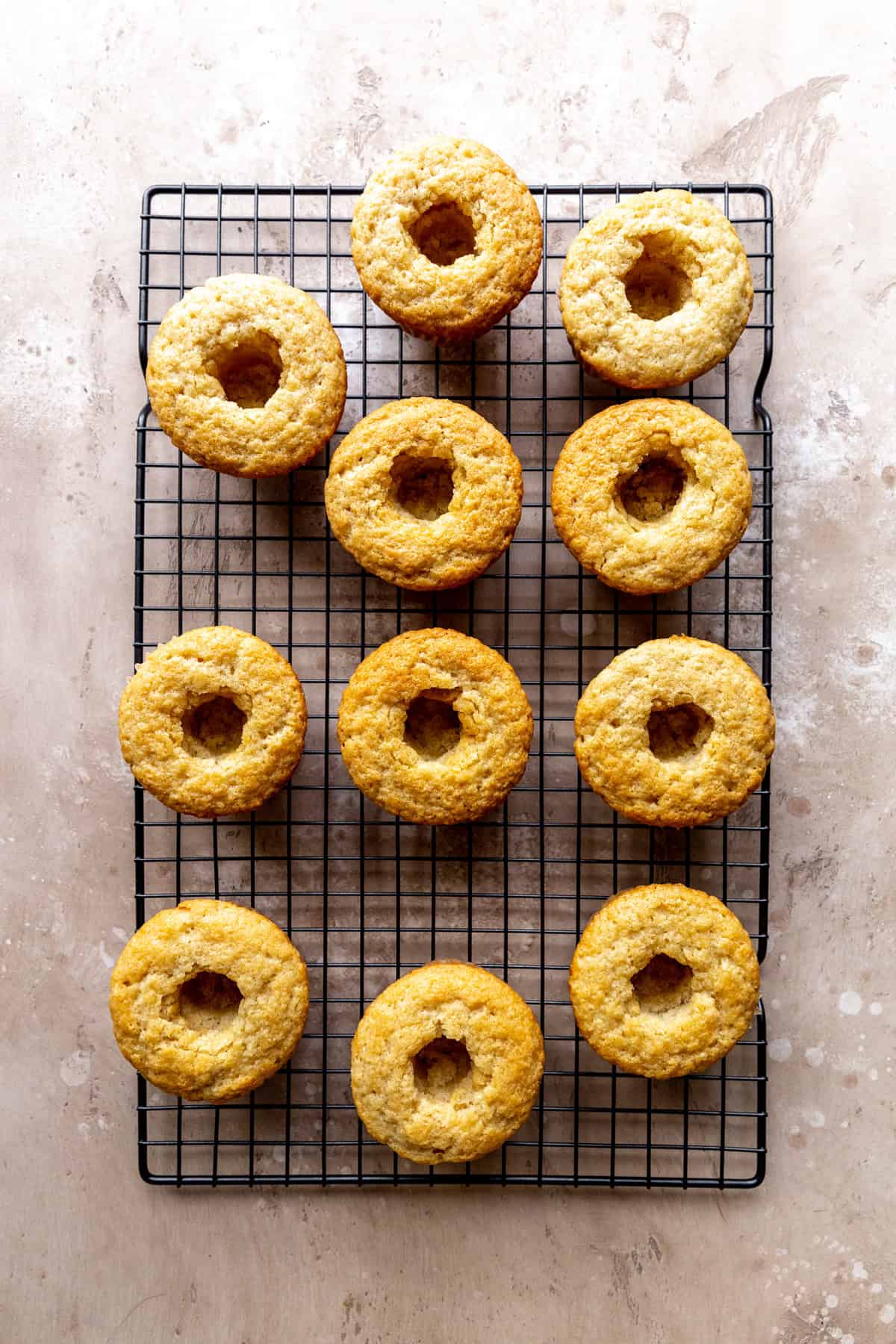 Cored vanilla cupcakes on a wire cooling rack.