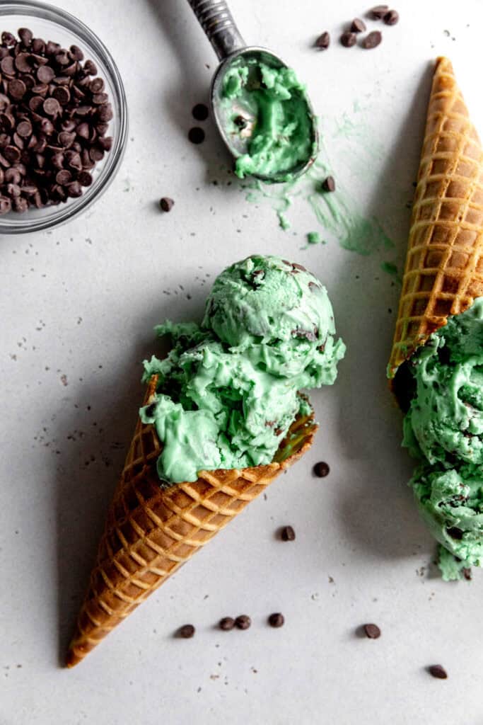 Waffle cone with mint chip ice cream and a bowl of mini chocolate chips.
