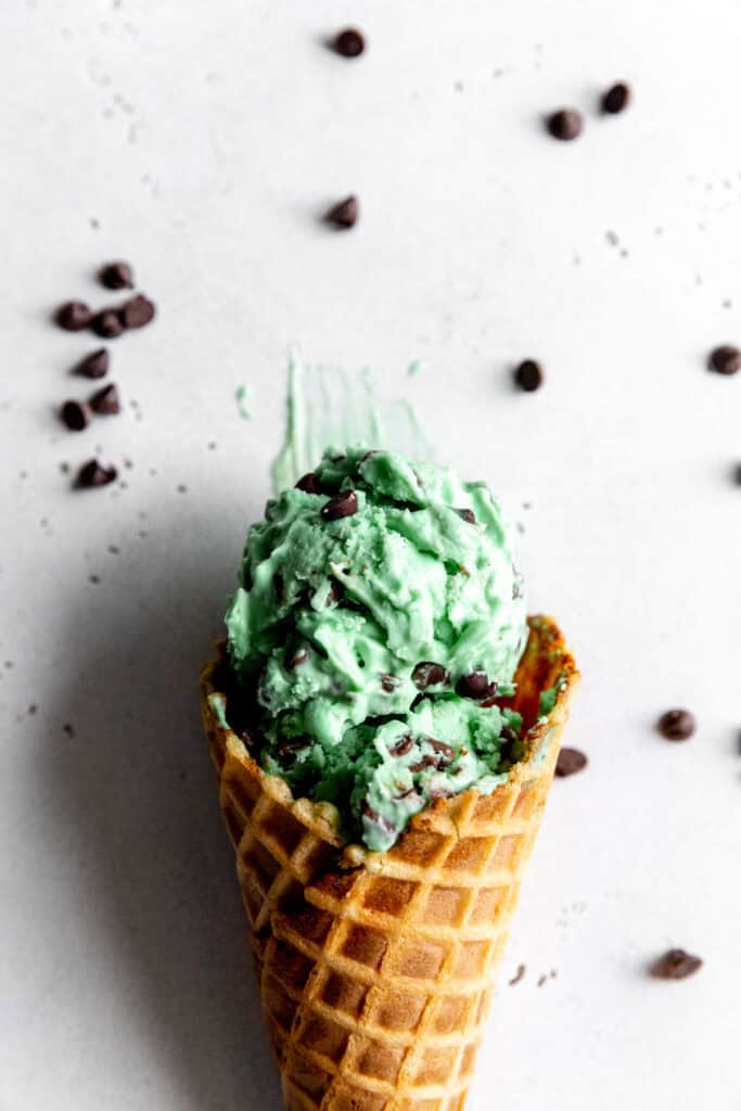 Waffle cone with one scoop of mint chip ice cream and mini chocolate chips.
