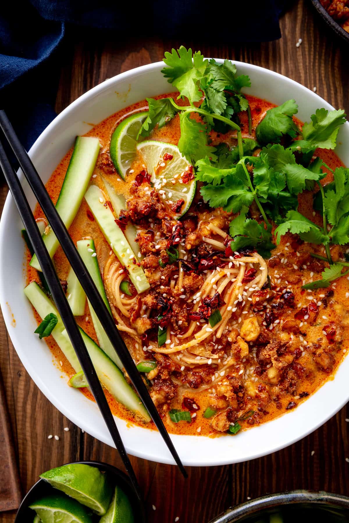 Bowl of miso curry ramen topped with crispy tofu, cucumber, cilantro and lime wedges.