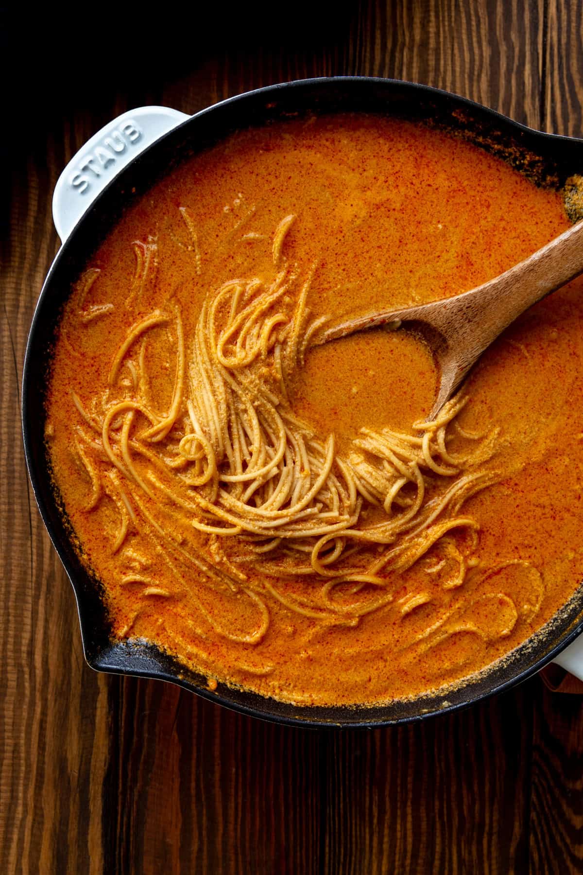 Ramen in a white skillet with a wooden spoon.