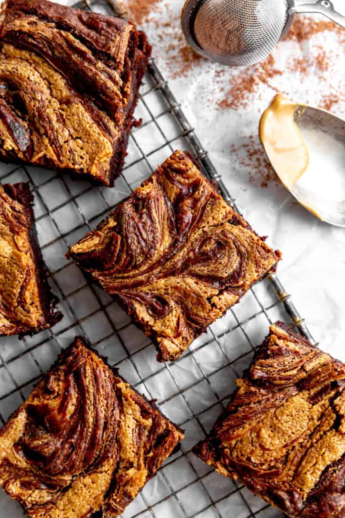 Peanut butter brownies on a wire rack and a spoonful of peanut butter.