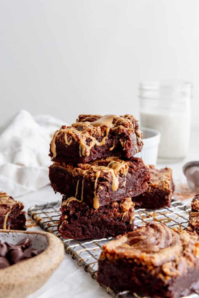 Stack of peanut butter brownies, a linen napkin and a cup of milk.