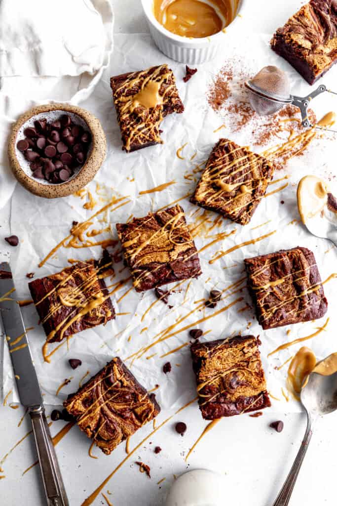 Peanut butter brownies on a white surface drizzled in melted peanut butter.