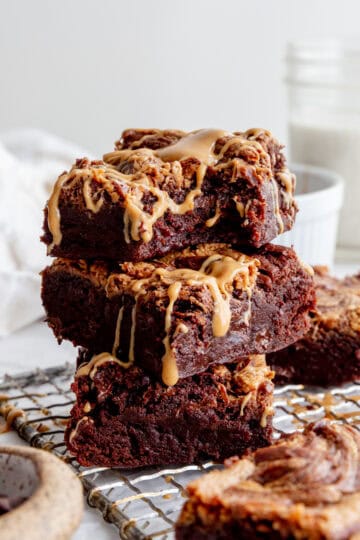 Stack of peanut butter brownies, a cup of milk and a linen napkin.