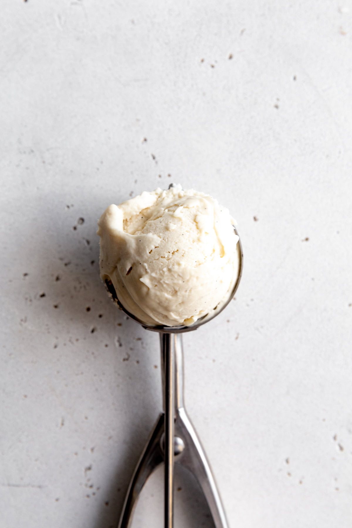 Ice cream scoop full of vanilla ice cream.