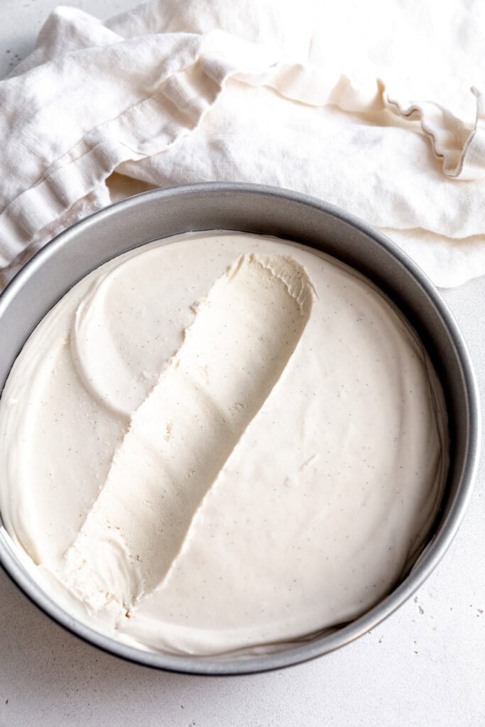 Cake pan of vanilla ice cream with a scoop missing and a white linen napkin.