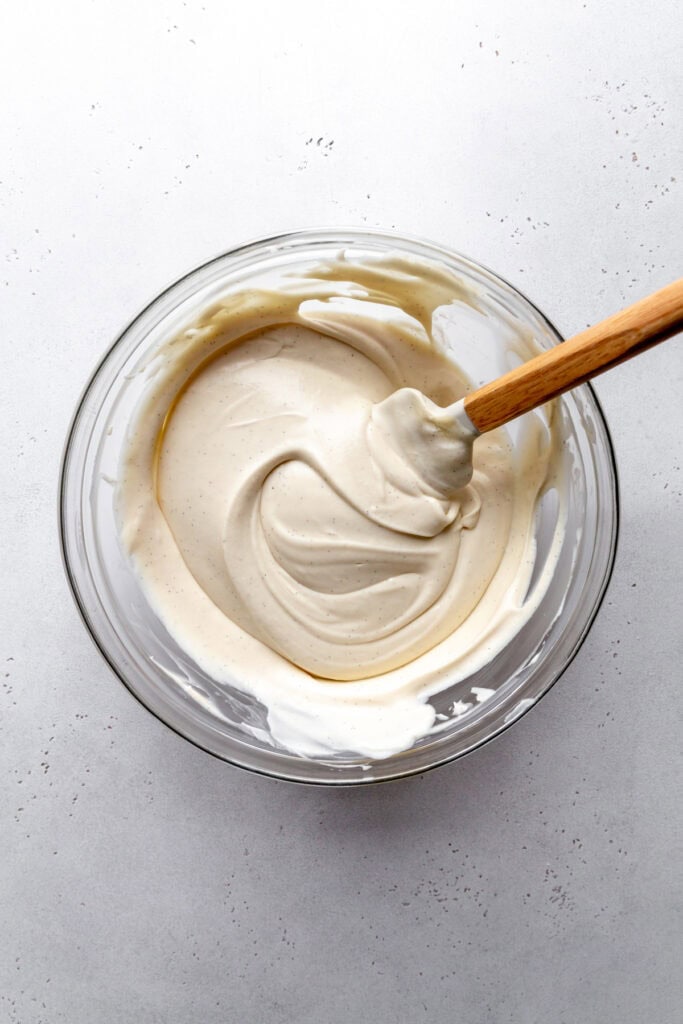 Vegan vanilla ice cream base in a glass bowl with a rubber spatula.