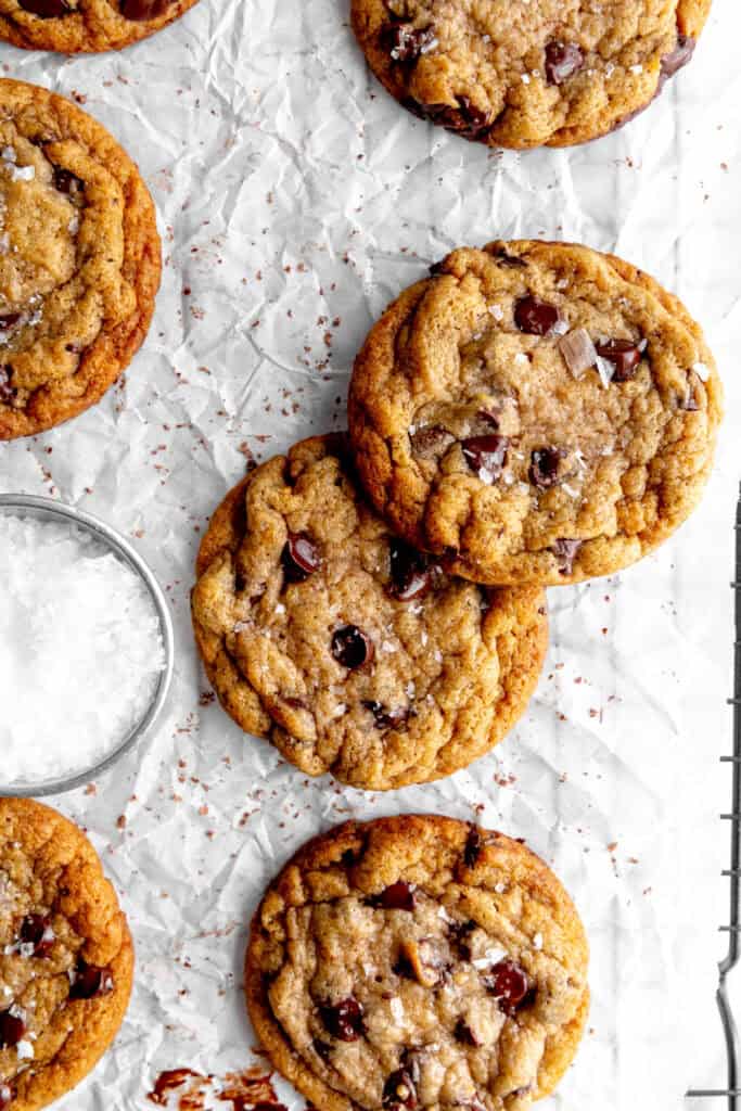 Banana chocolate chip cookies on a wire rack with a cup of flaky salt.