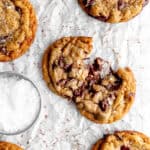 Banana chocolate chip cookie broken in half and a cup of flaky salt.