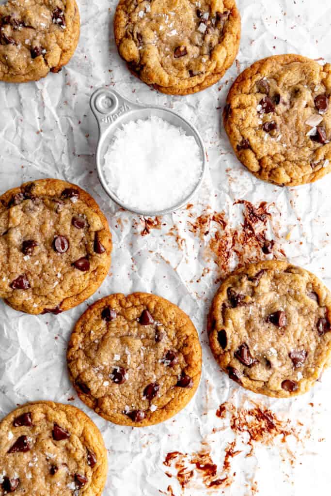 Gooey banana chocolate chip cookies on a white surface with flaky salt.