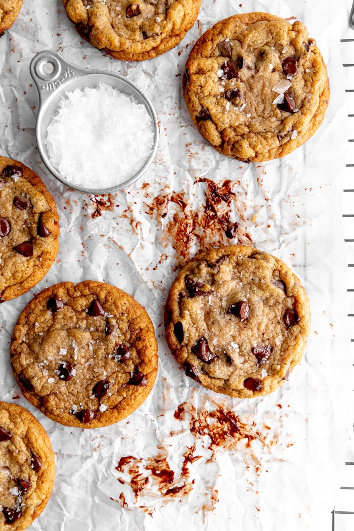 Gooey banana chocolate chip cookies on a wire rack with flaky salt.