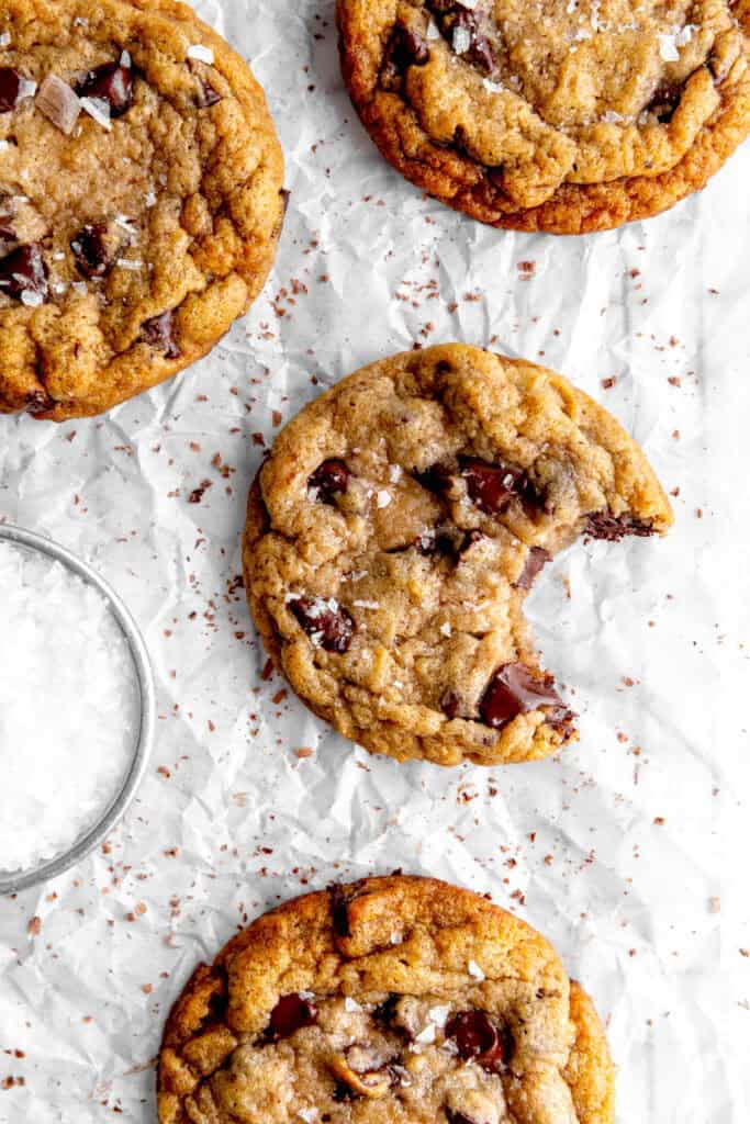 Banana chocolate chip cookie with a bite taken out of it and a cup of flaky salt.