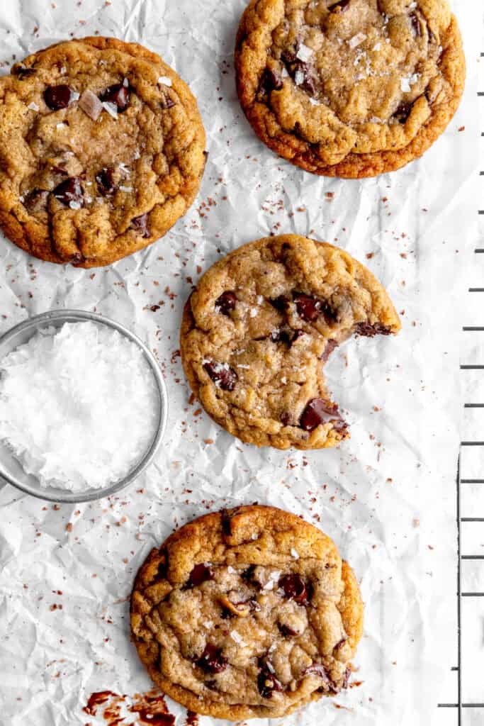 Banana chocolate chip cookie with a bite taken out of it and a cup of flaky salt.