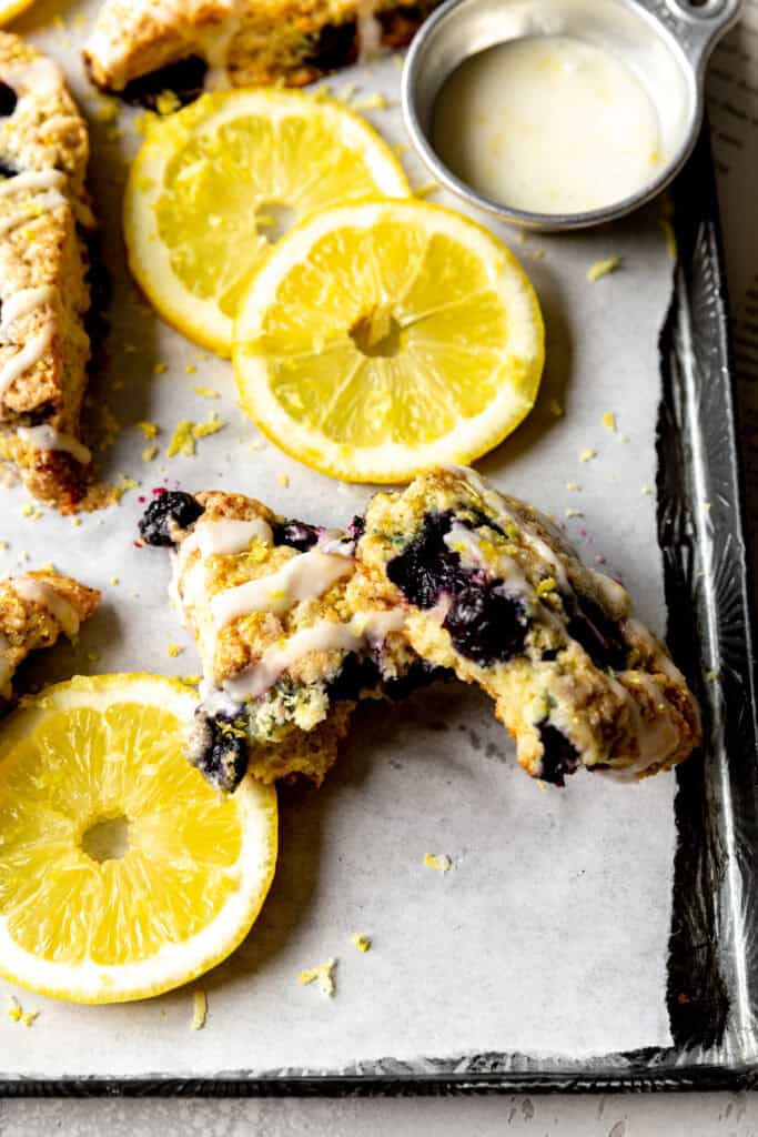 Lemon blueberry scone broken in half and lemon slices.