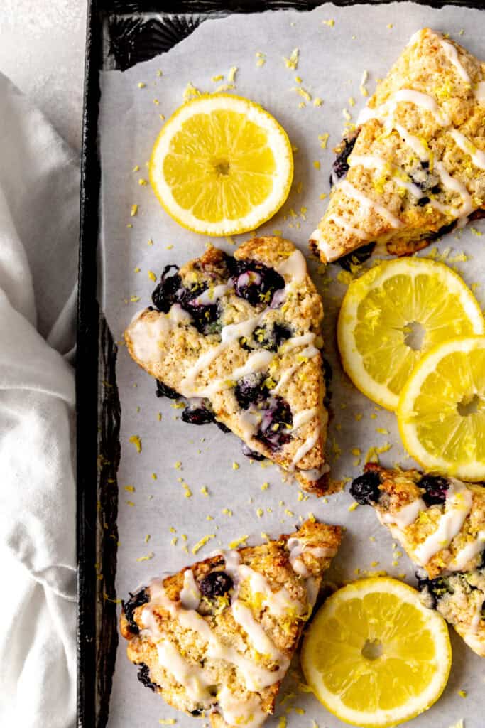 Lemon blueberry scones and lemon slices on a baking sheet.