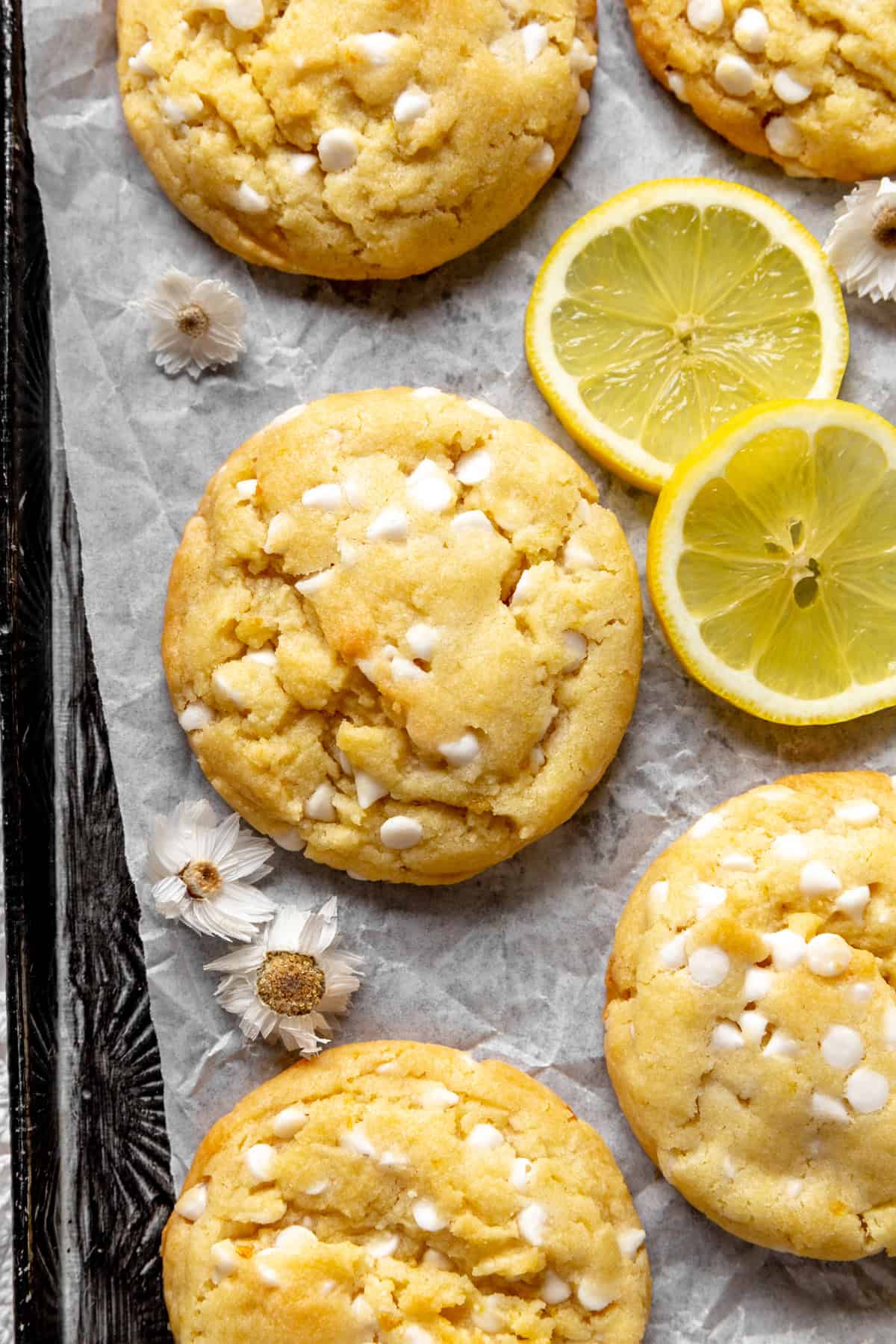 Lemon white chocolate cookies and lemon slices on a baking sheet.
