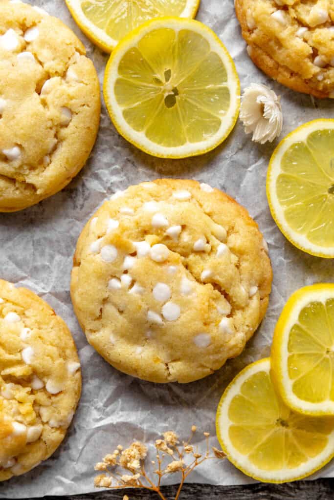 Lemon white chocolate cookies and lemon slices on a baking sheet.