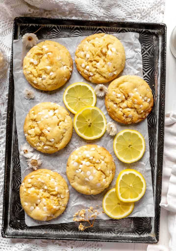Lemon white chocolate cookies, lemon slices and two glasses of milk.