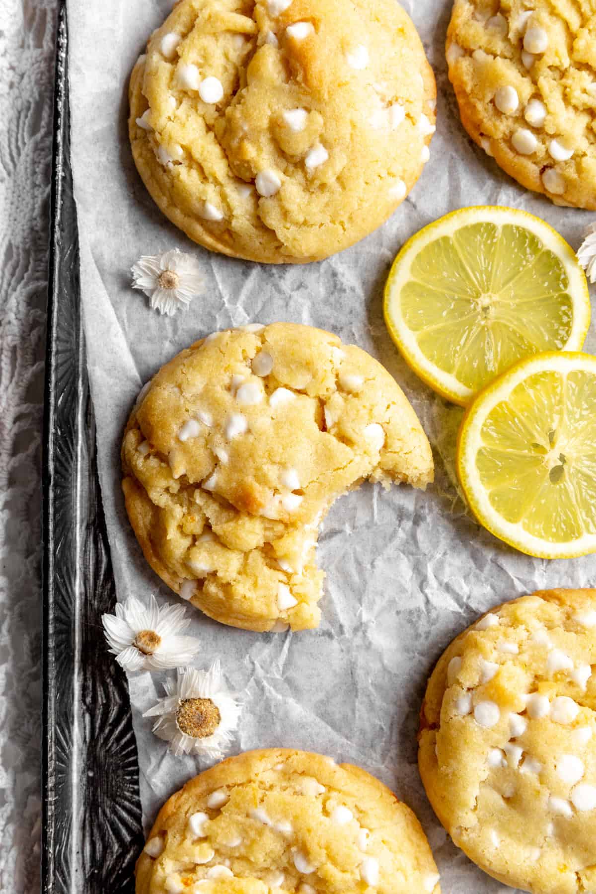 Lemon white chocolate cookie with a bite taken out of it and two lemon slices.