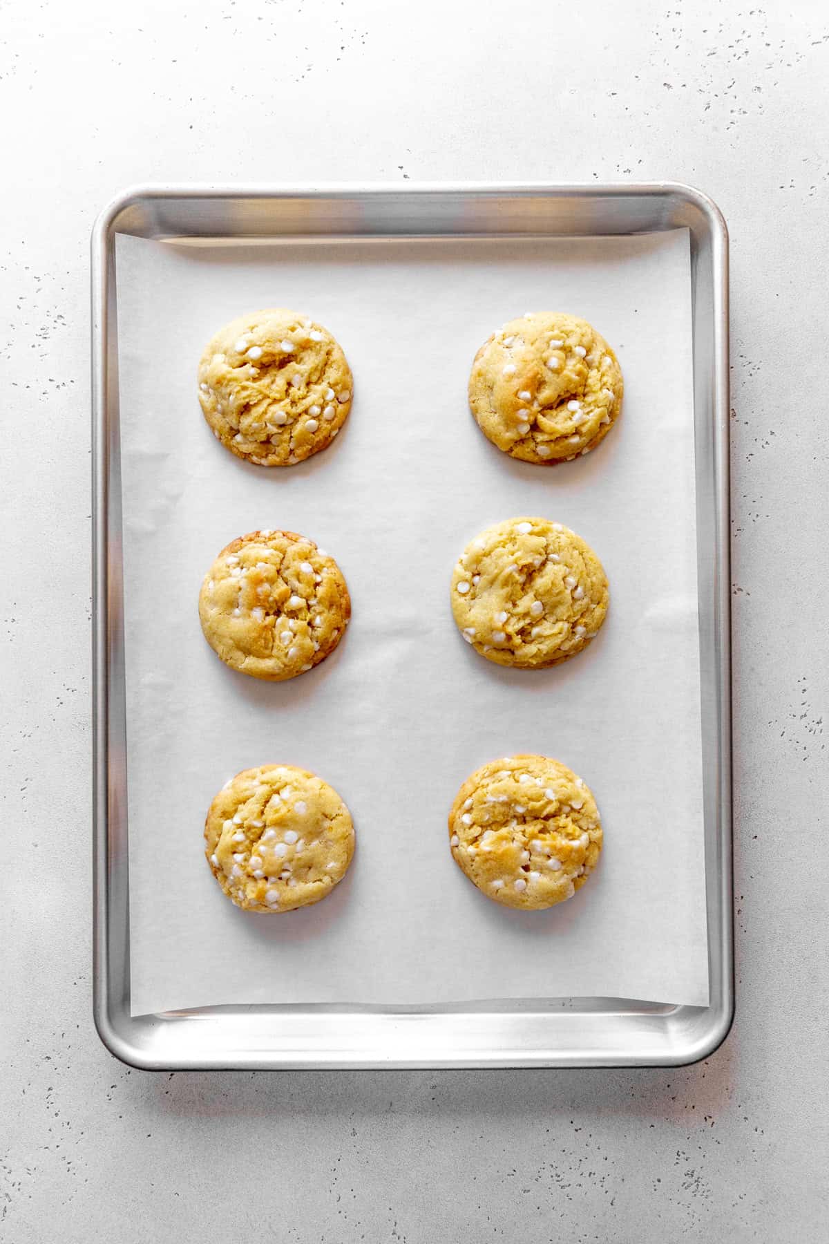 Baked lemon white chocolate cookies on a baking sheet.