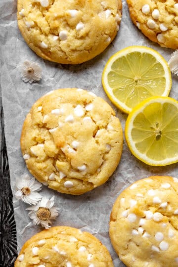 Lemon white chocolate cookies on a baking sheet with lemon slices.