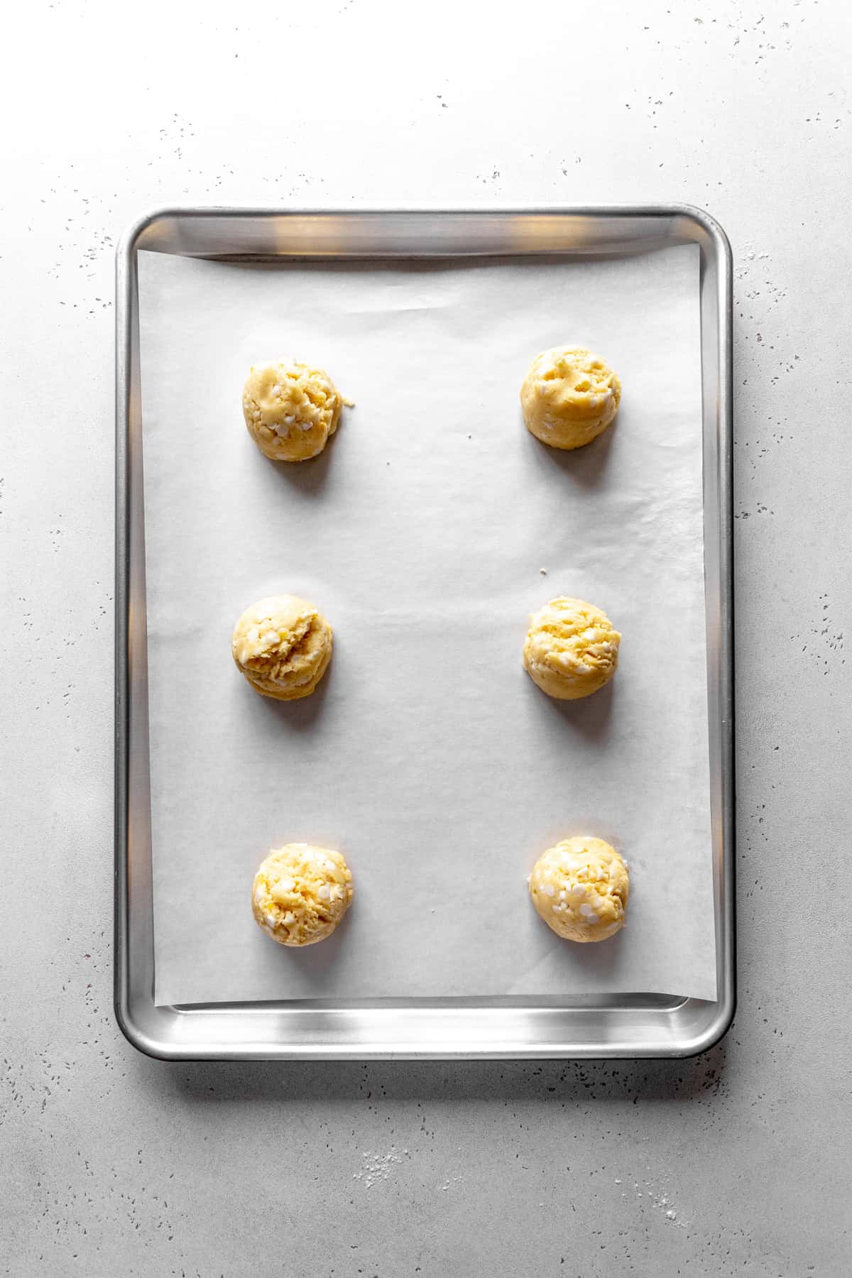 Unbaked lemon white chocolate cookies on a baking sheet.