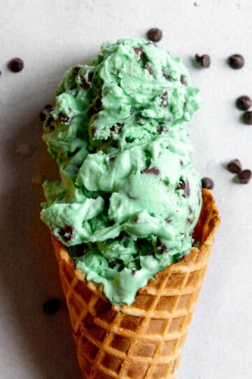Waffle cone with two scoops of mit chip ice cream.