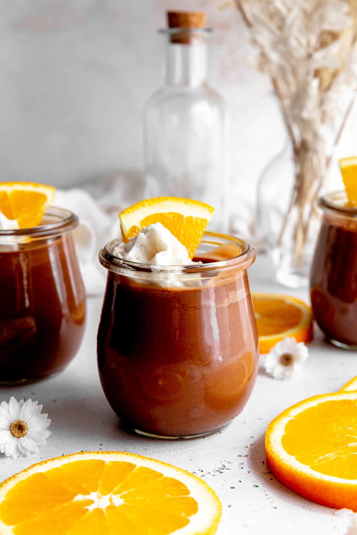 Jar of chocolate mousse topped with a triangle orange slice.