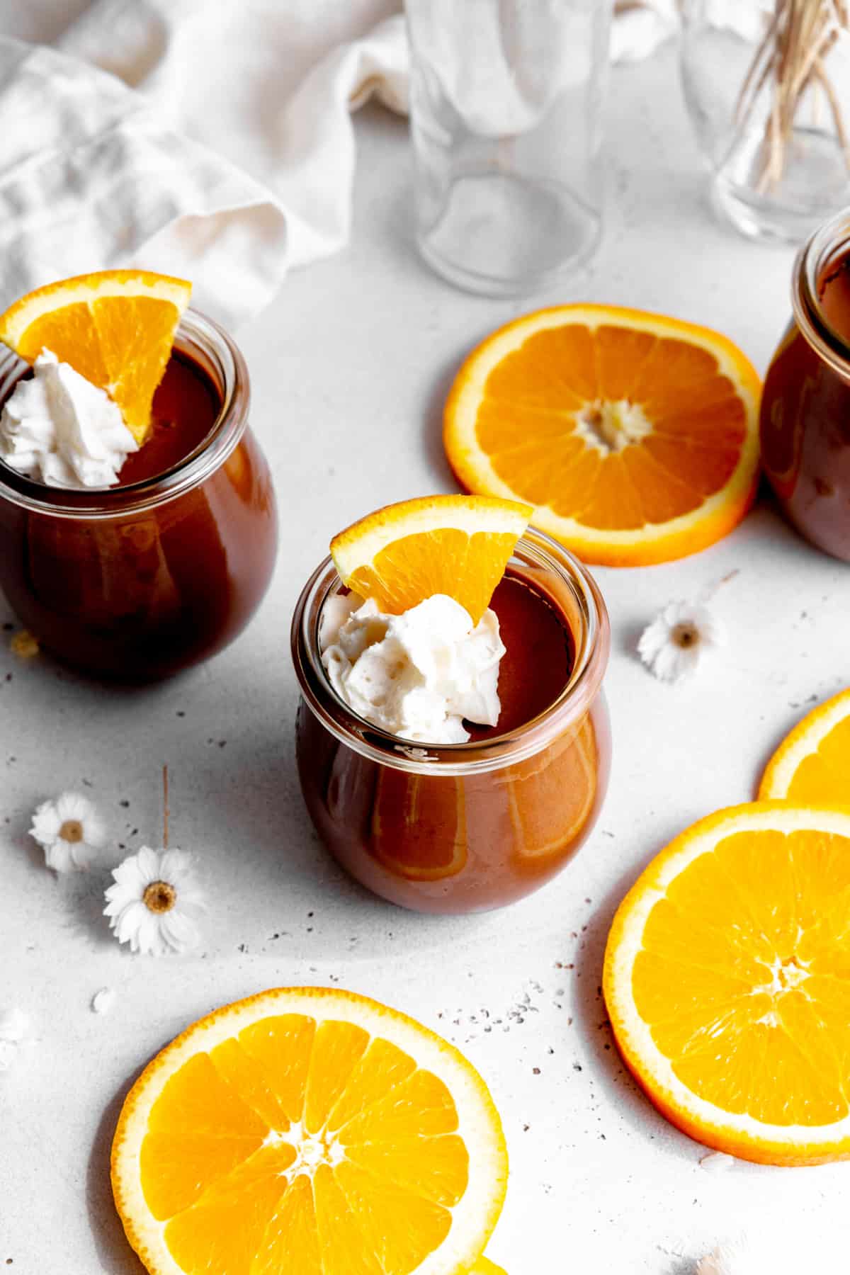 Orange slices surrounding a jar of chocolate mousse topped with whipped cream.