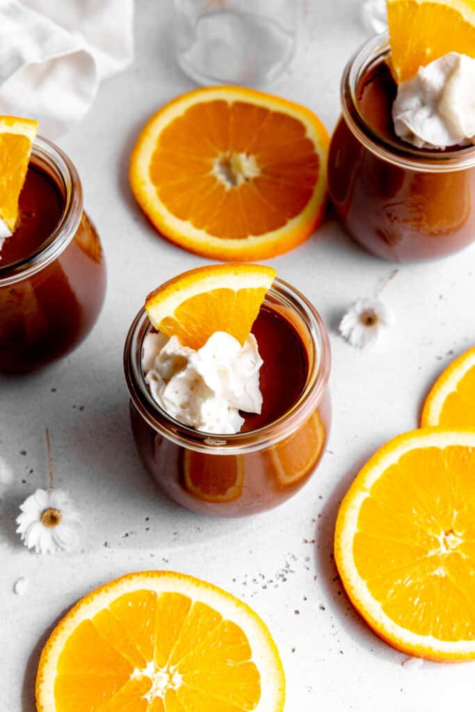 Orange slices surrounding a jar of chocolate mousse topped with whipped cream.
