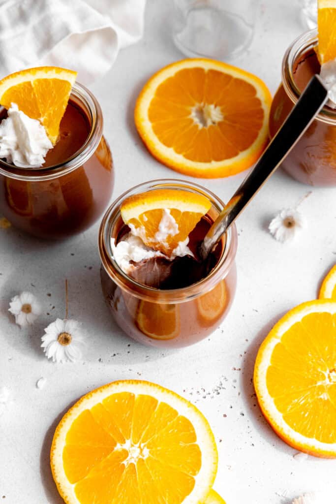 Spoon digging into a jar of orange chocolate mousse.
