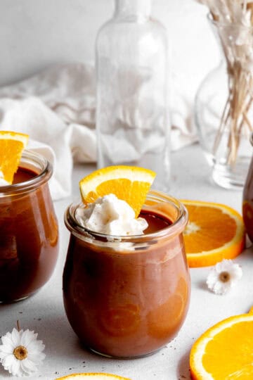 Glass jars of chocolate mousse and orange slices.
