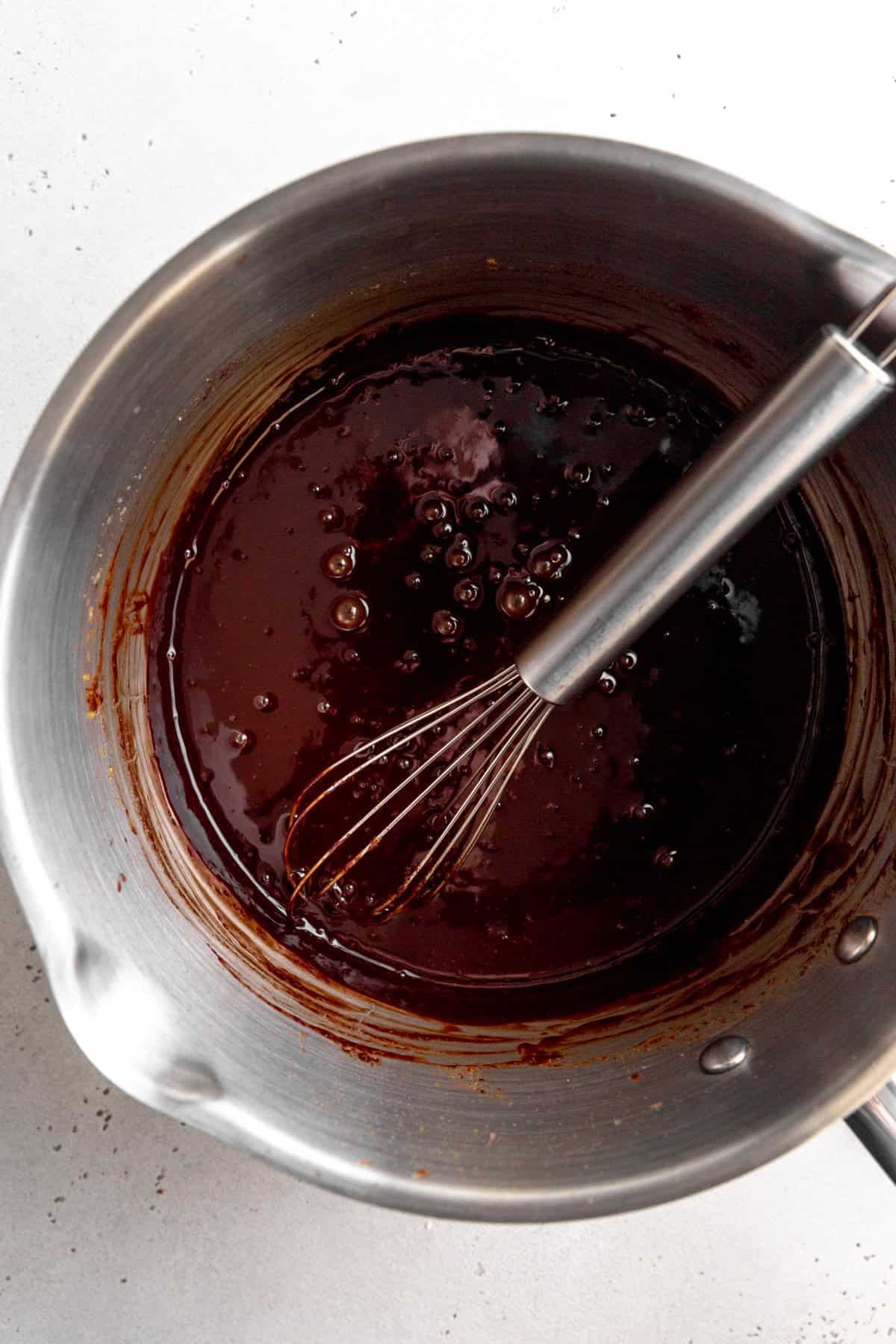 Melted chocolate in a steel pan with a wire whisk.