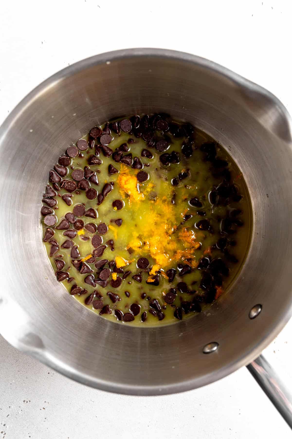Steel pan of chocolate chips, orange juice and orange zest.