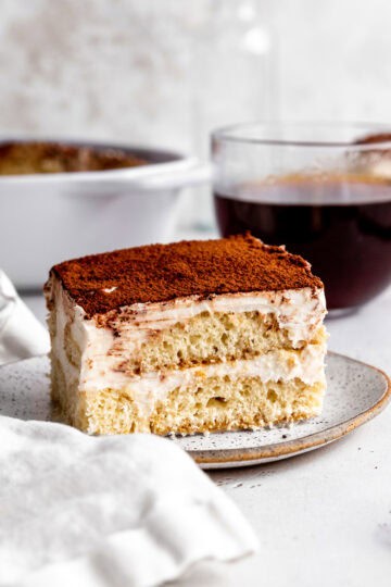 Slice of tiramisu on a plate and a mug of coffee.