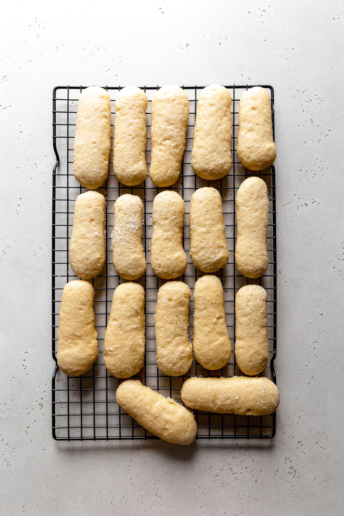 Baked lady fingers on a wire rack.