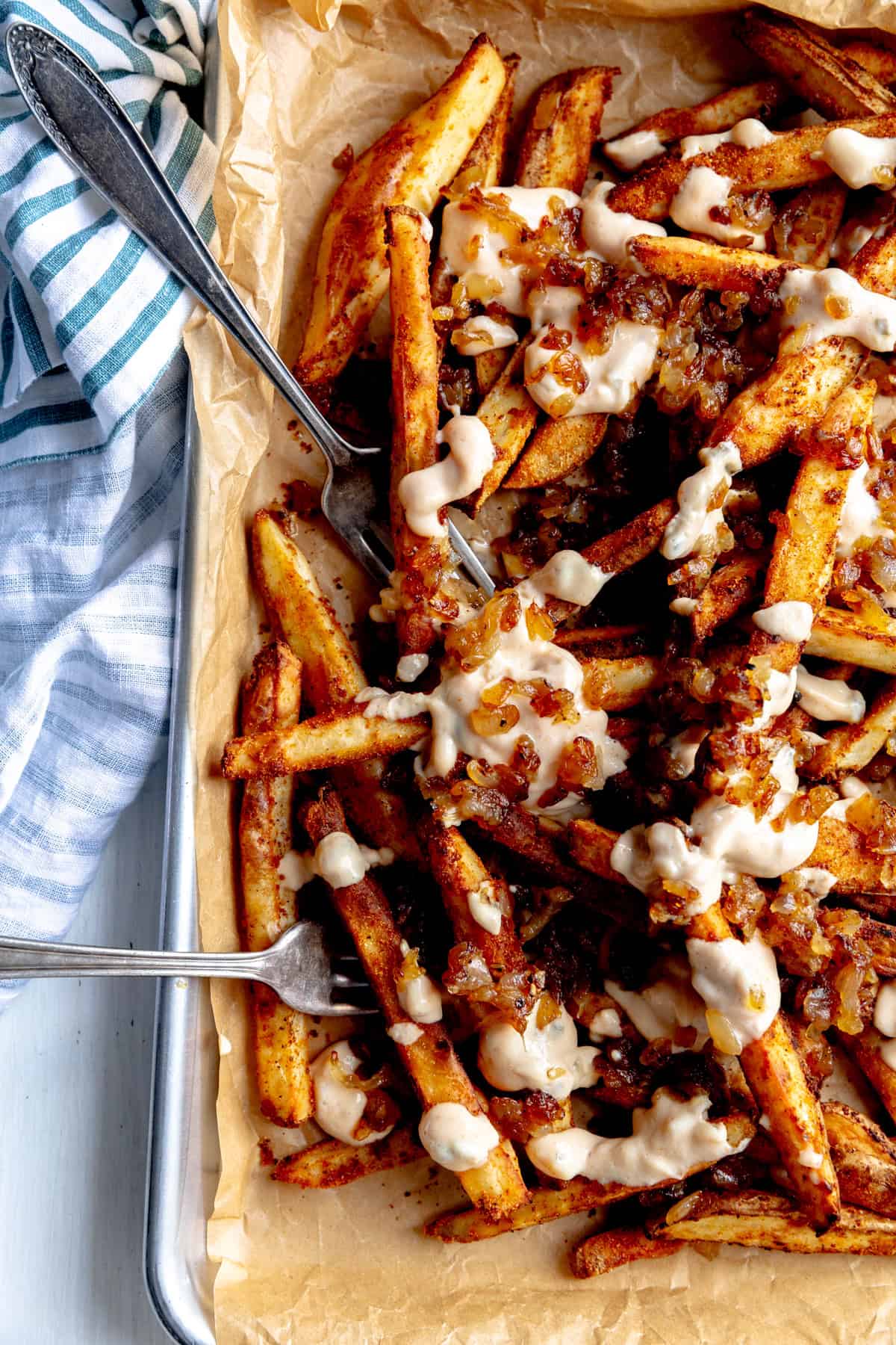 Two forks digging into a plate of animal fries.