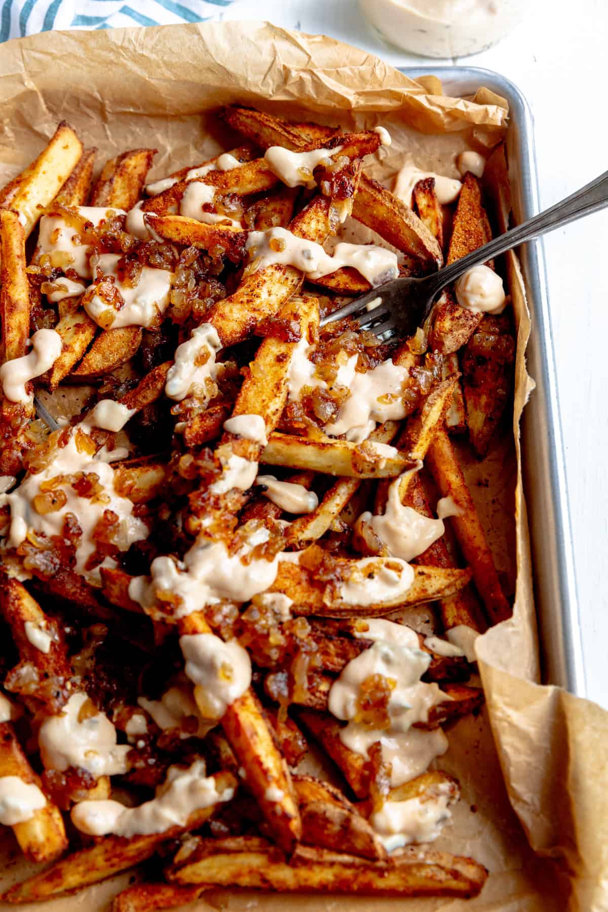 Fork stabbing into animal fries on a baking sheet.