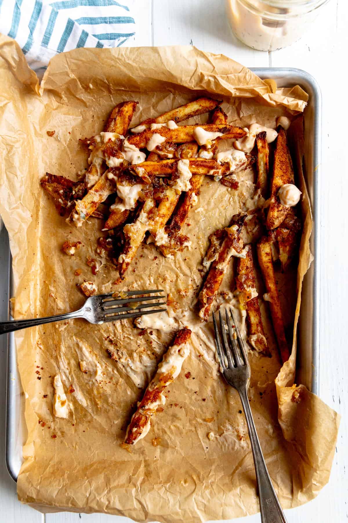 Baking sheet with a few remaining fries and two forks.