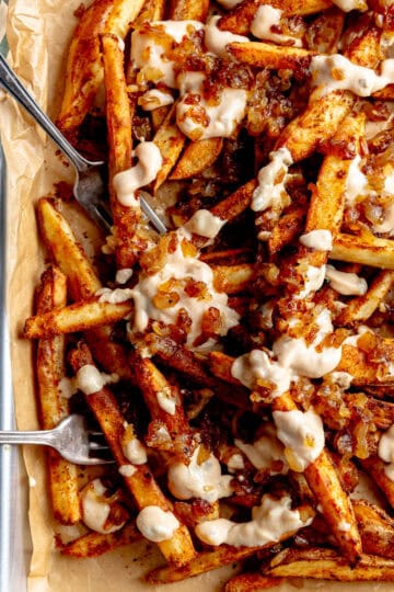 Animal fries on a baking sheet with two forks and a striped linen napkin.
