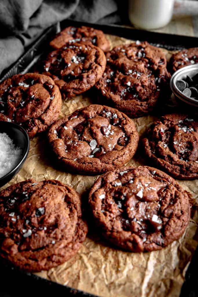 Double chocolate cookies on a baking sheet, a jug of milk and a linen napkin.